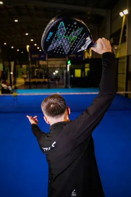 Jugador sacando en una cancha de pádel techada