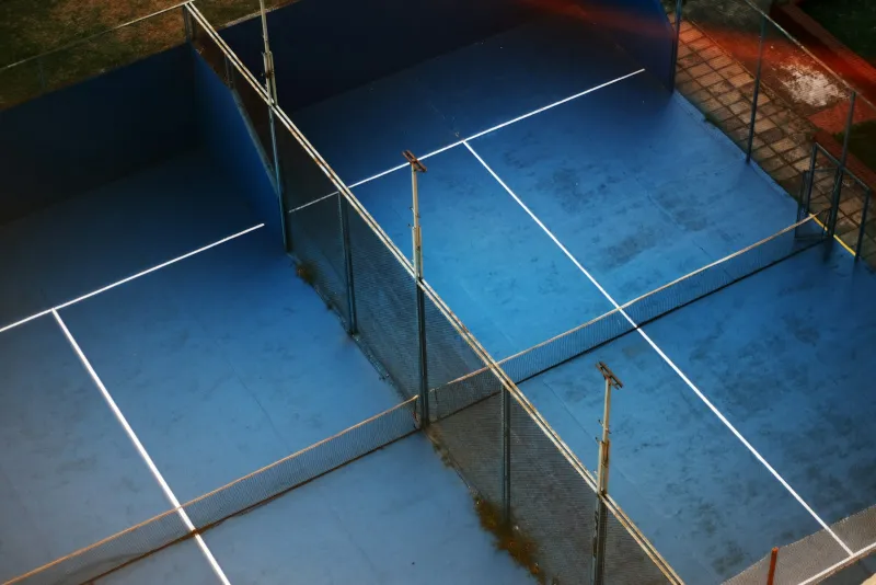 Canchas de pádel con piso azul y muros de cristal vistas desde arriba